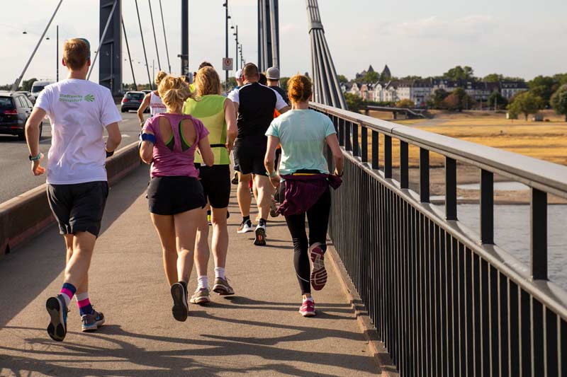 Eine Laufgruppe joggt auf einer Brücke